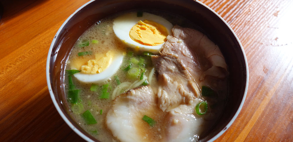 ますたにのラーメンにゆで卵と、ネギの小口切りを入れて、紅茶豚のスライス。
