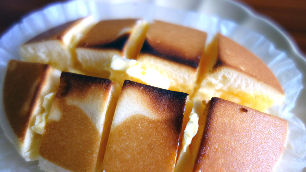 焼いた北海道チーズ蒸しケーキにカットしたバターをはさむ