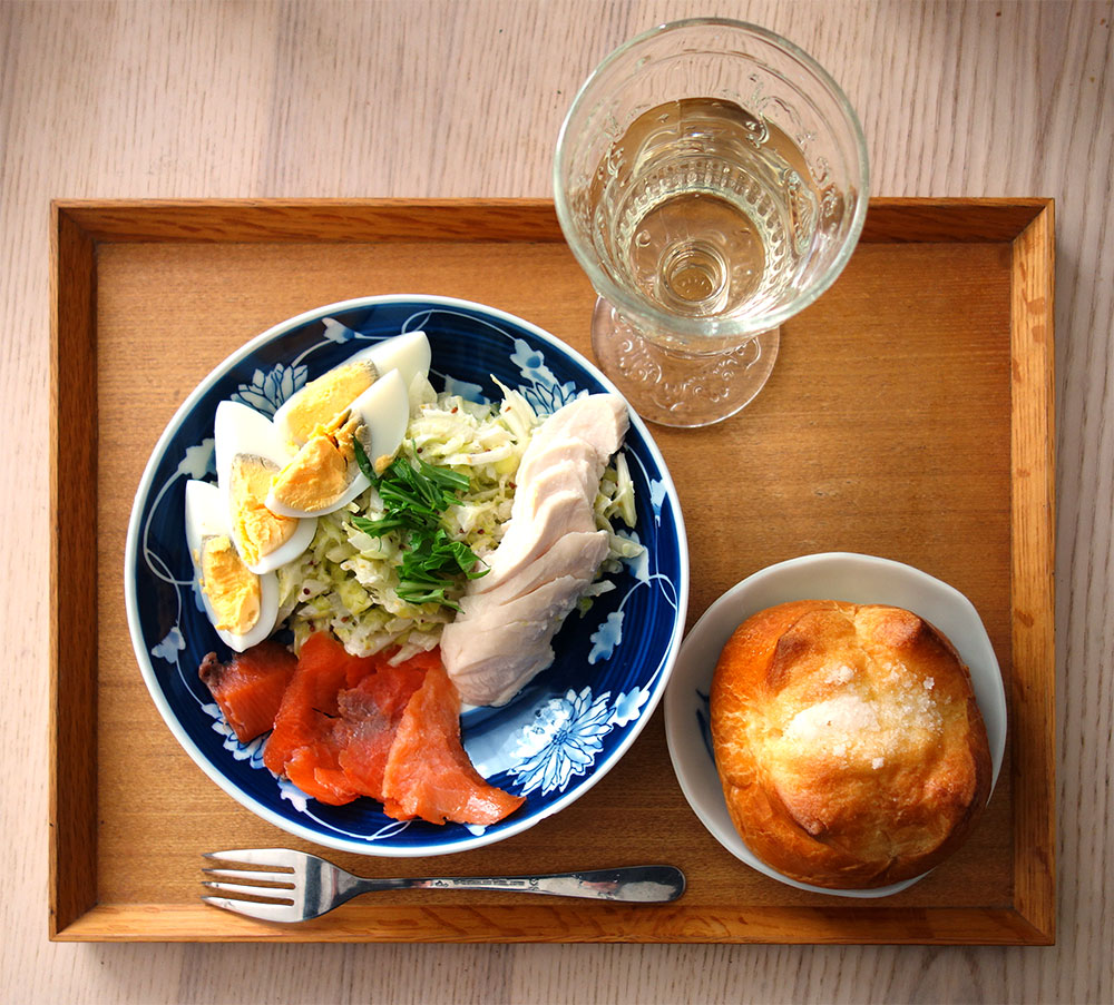 無印良品の木のトレーにキャベツと玉ねぎのマスタードマヨサラダとゆで卵・低温調理の鶏むね肉。スモークサーモン。　ブリオッシュと原茂ワインさんのデラウエア白ワイン。