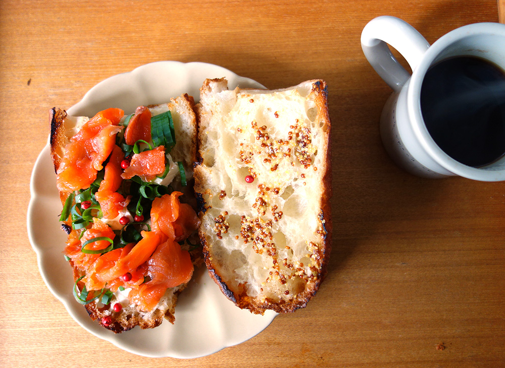 バゲットに粒マスタードとクリームチーズ。スモークサーモンとピンクペッパー、レモンとオリーブオイルでサンドイッチ。ホットコーヒーを添えて。